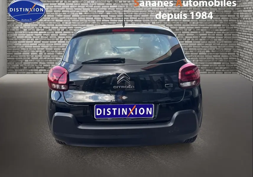 Vue arrière d'une Citroën C3 noire 2023 avec logo et feux arrière arrondis dans un décor urbain.