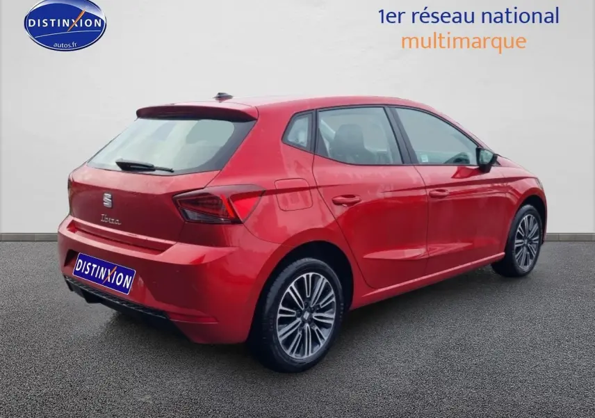 Vue 3/4 arrière droite d'une SEAT Ibiza rouge désir avec jantes alliage et feux arrière LED triangulaires.