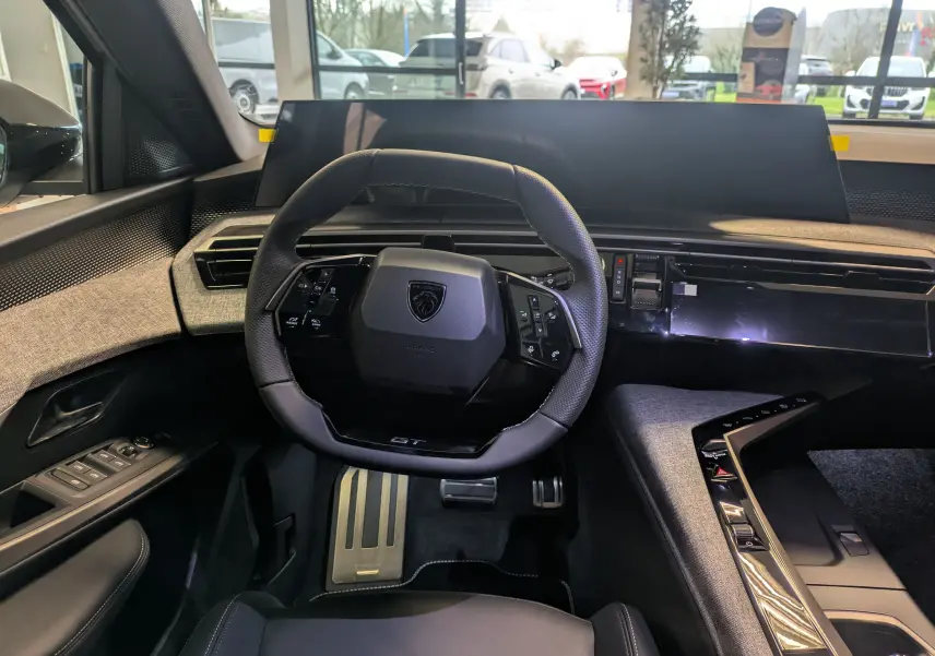 Vue intérieure du poste de conduite du Peugeot 3008 blanc Okenite, avec volant compact et tableau de bord numérique épuré.
