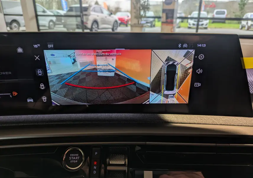 Vue intérieure du tableau de bord du Peugeot 3008 blanc, écran affichant la caméra de recul et la vision 360° en marche.