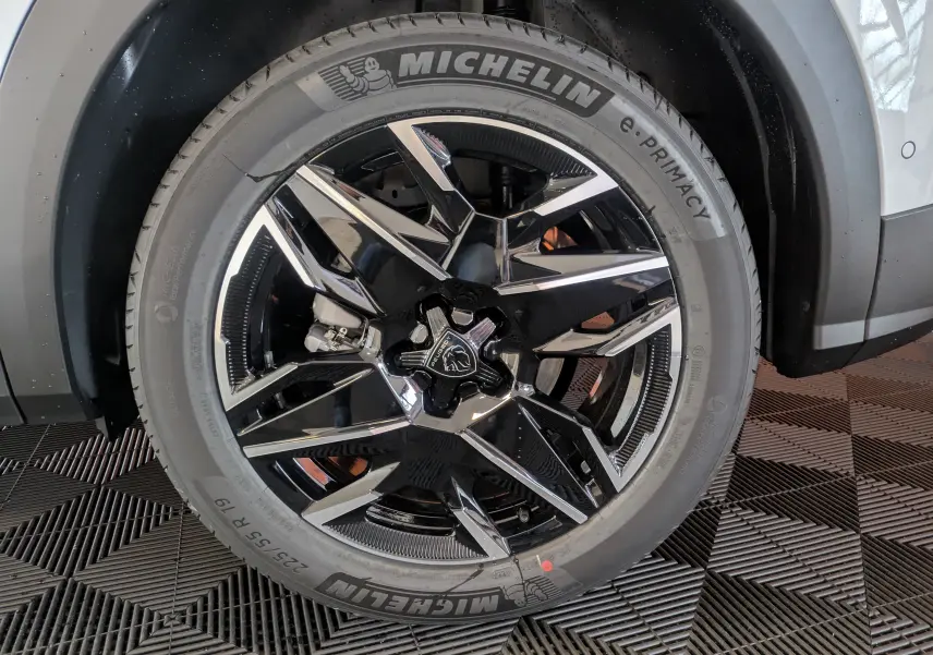 Gros plan sur la roue avant droite du Peugeot 3008 blanc Okenite, avec jante alliage noire et détails chromés.