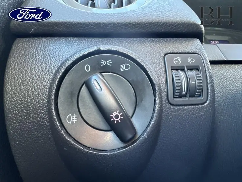 Commande d'éclairage noir en gros plan sur le tableau de bord d'un Volkswagen Tiguan gris Crypton, vue intérieure côté gauche.