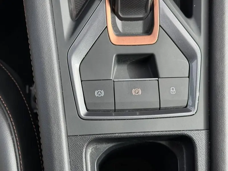 Gros plan sur la console centrale du CUPRA Formentor 1.5 eTSI Hybrid 2025 avec boutons de frein à main et verrouillage.