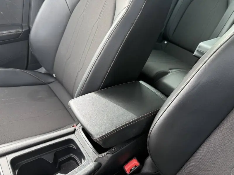 Gros plan sur l'accoudoir central et sièges noirs à surpiqûres contrastées dans le CUPRA Formentor blanc Nevada 2025.