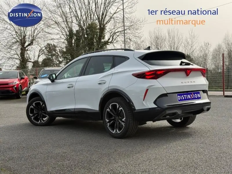 Vue 3/4 arrière droite d'un CUPRA Formentor blanc Nevada métallisé avec jantes noires et feux arrière LED distinctifs.