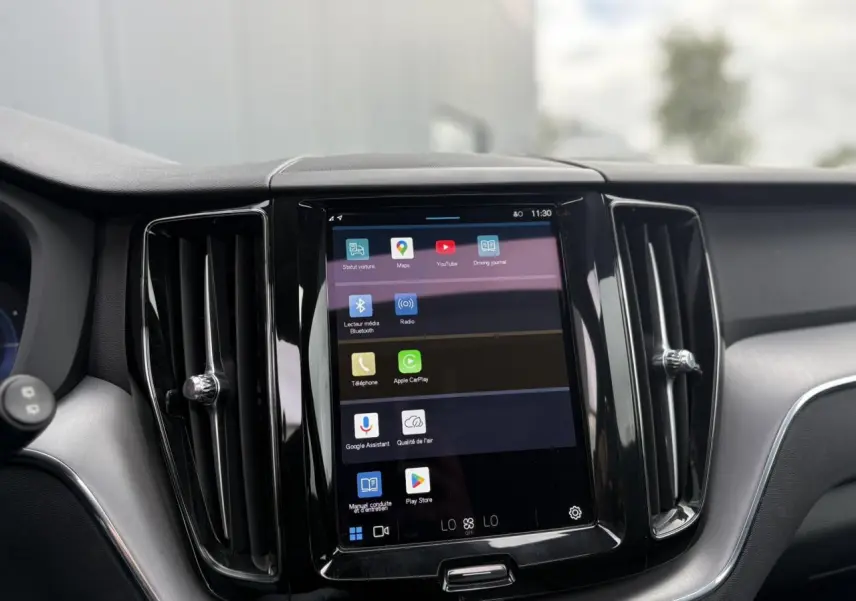 Vue rapprochée de l’écran tactile central du tableau de bord du Volvo XC60 rouge, entouré de deux aérateurs verticaux noirs.