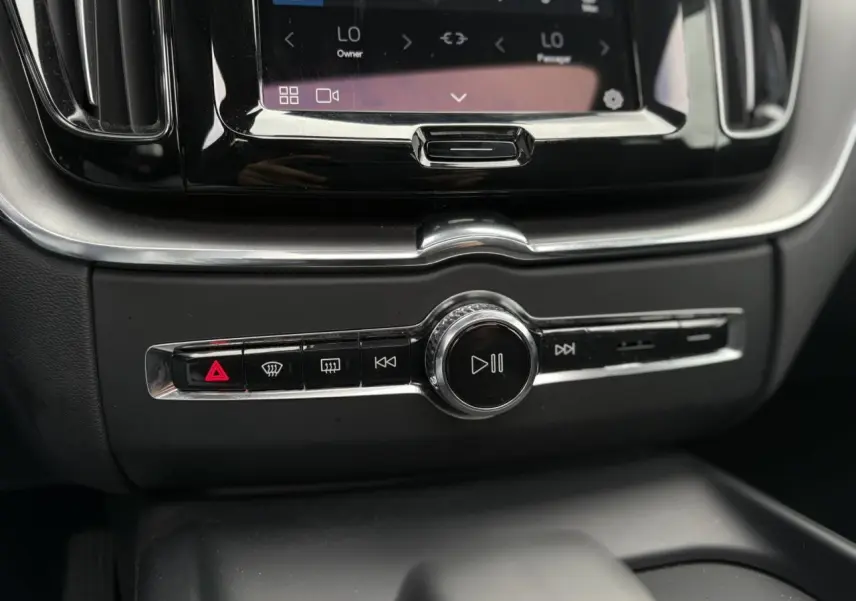 Gros plan sur la console centrale noire du Volvo XC60 2024, avec commandes multimédia et climatisation tactile.