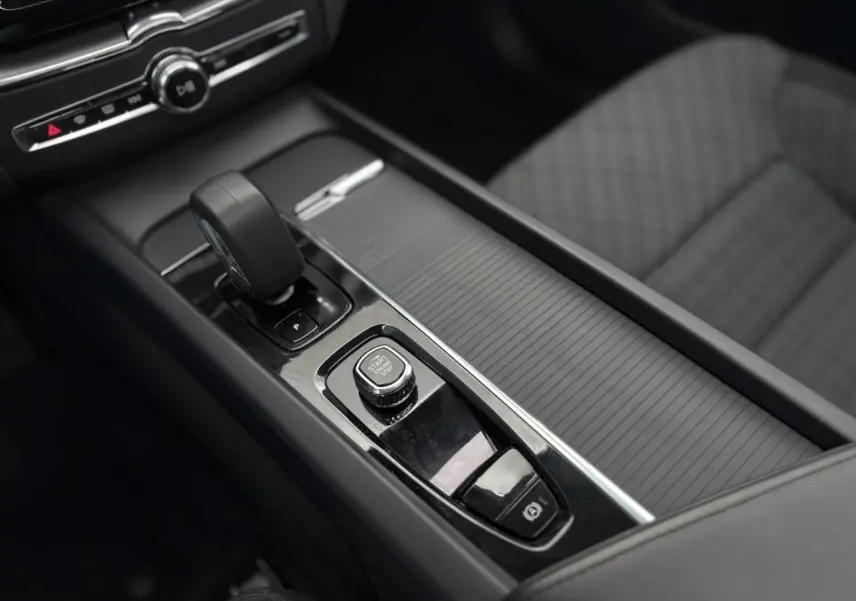 Vue rapprochée de la console centrale noire du Volvo XC60 T6 AWD PHEV 2024 avec levier de vitesse et bouton start/stop.