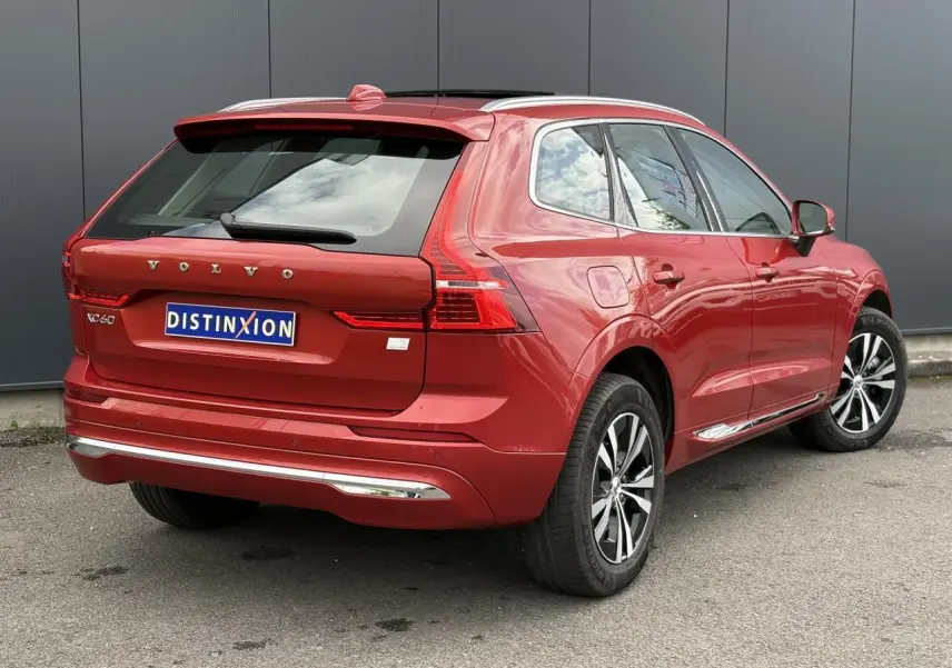 Vue 3/4 arrière droite du Volvo XC60 rouge Fusion 2024 avec jantes alliage et contours chromés des vitres.