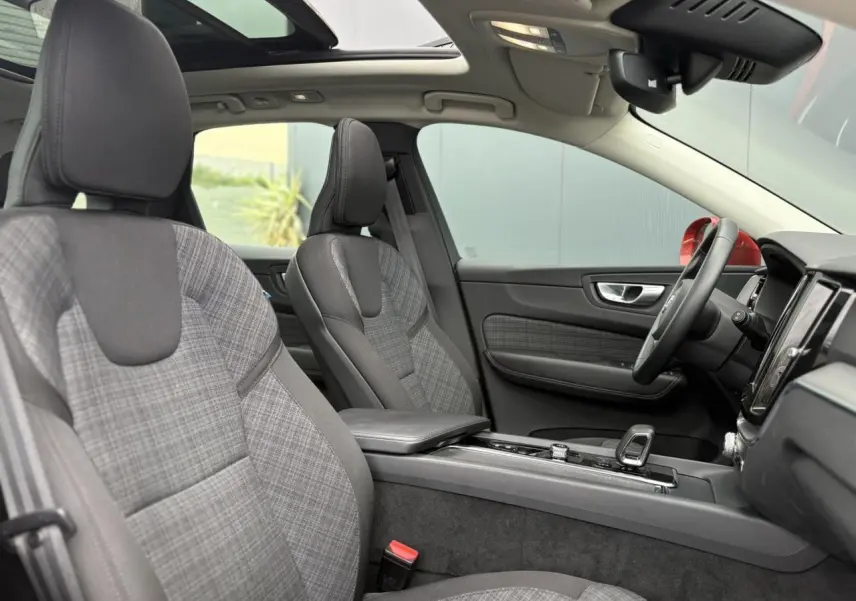 Vue intérieure côté droit du Volvo XC60 2024, sièges tissu gris à motif carreaux et toit ouvrant panoramique.