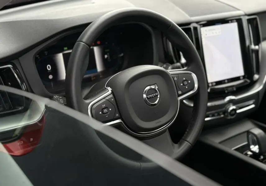 Vue rapprochée du volant noir et du combiné d'instruments digital du Volvo XC60 T6 AWD PHEV 2024.