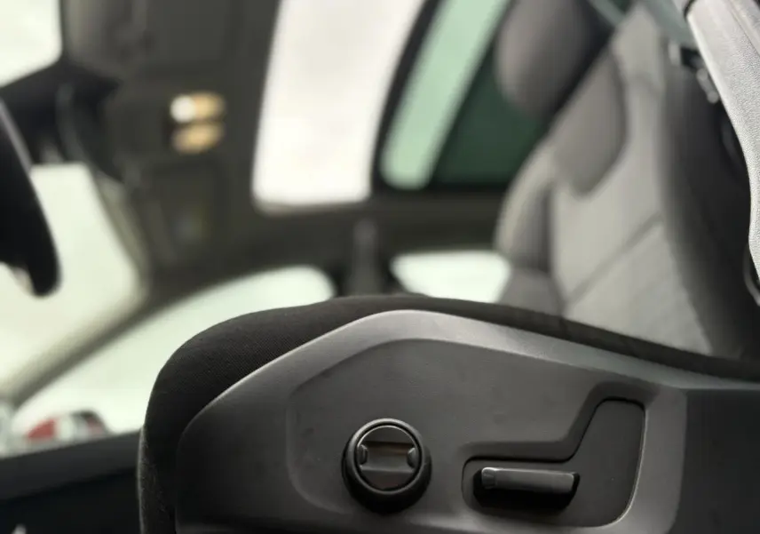 Détail des commandes de réglage électrique du siège avant côté conducteur dans un Volvo XC60 rouge Fusion 2024.