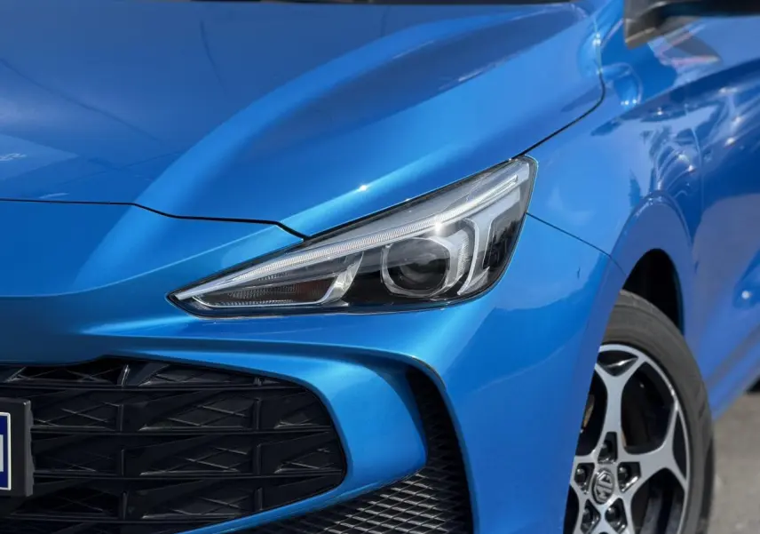 Gros plan sur l'avant droit bleu Como du MG3 1.5 Hybrid+ 195 Comfort, mettant en valeur le phare LED et la calandre noire.