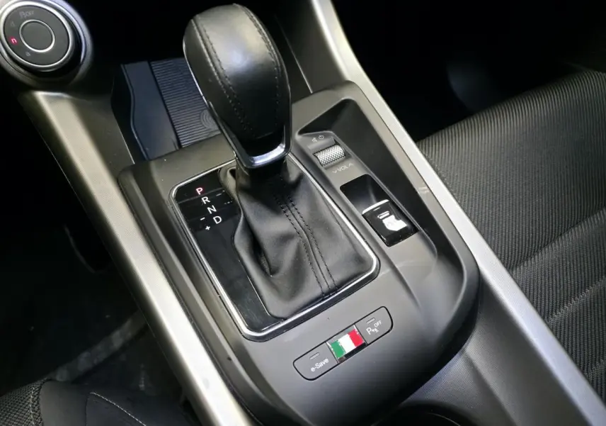 Gros plan sur la console centrale de l'Alfa Romeo Tonale 2024, levier de vitesses noir et logo tricolore italien.