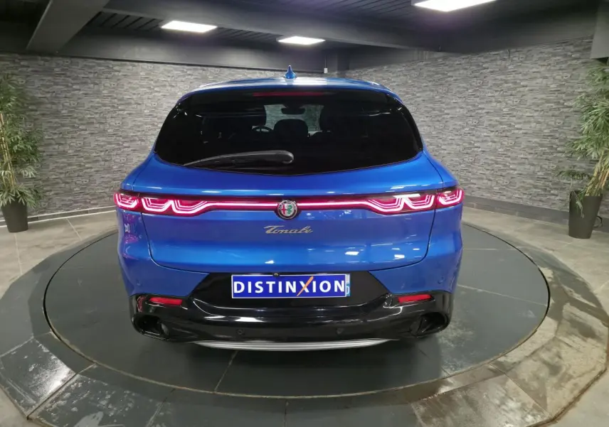 Vue arrière d'une Alfa Romeo Tonale 2024 bleue métallisée avec feux arrière LED et logo central lumineux.