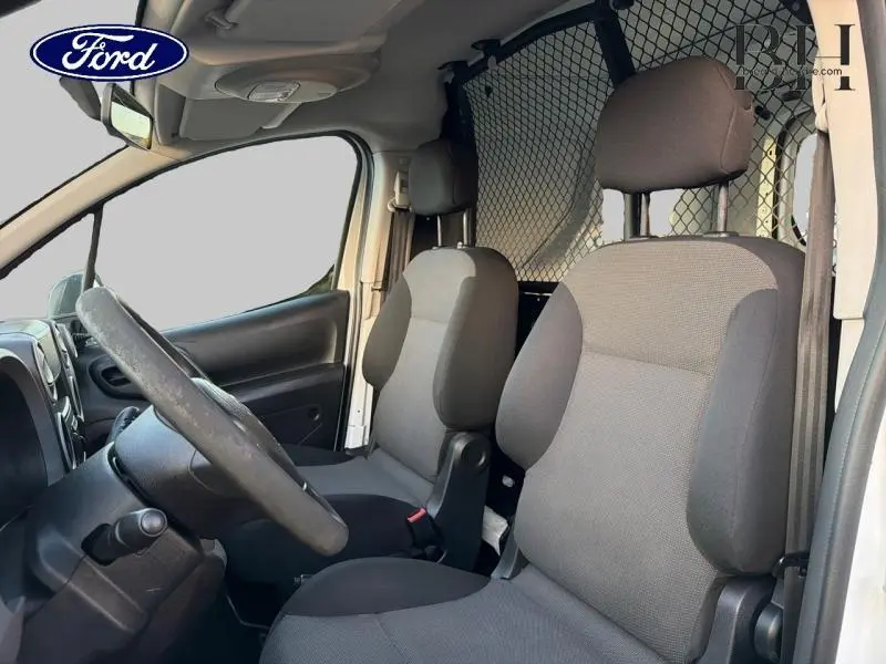Vue intérieure côté conducteur du Citroën Berlingo blanc avec sièges gris et cloison tubulaire derrière les sièges.