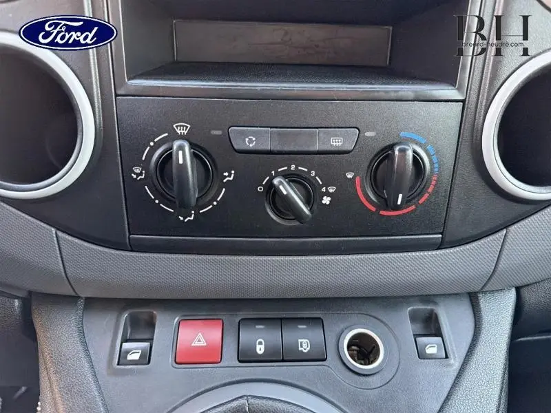 Tableau de bord noir avec commandes de climatisation et boutons de verrouillage, intérieur d'un Citroën Berlingo blanc.