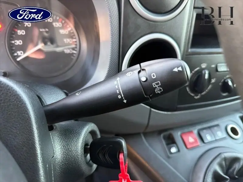 Gros plan sur la commande d’essuie-glace et le tableau de bord intérieur gris d’un Citroën Berlingo blanc, version Confort.