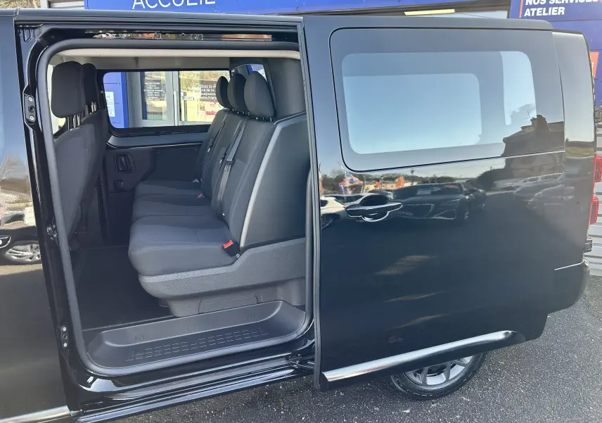 Vue latérale droite d'un Citroën Jumpy cabine approfondie noir avec porte coulissante ouverte montrant les sièges arrière tissu.
