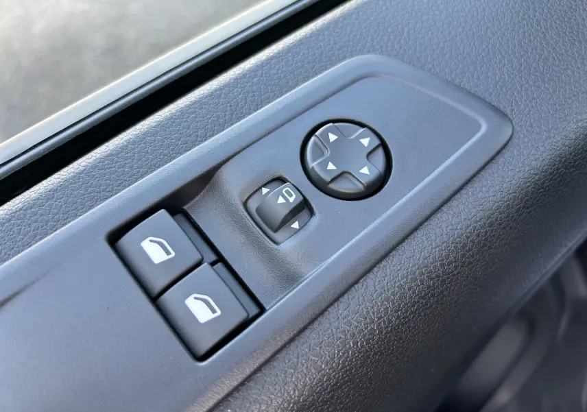 Gros plan sur les commandes de réglage des rétroviseurs et des vitres côté conducteur d’un Citroën Jumpy Cabine Approfondie noir.