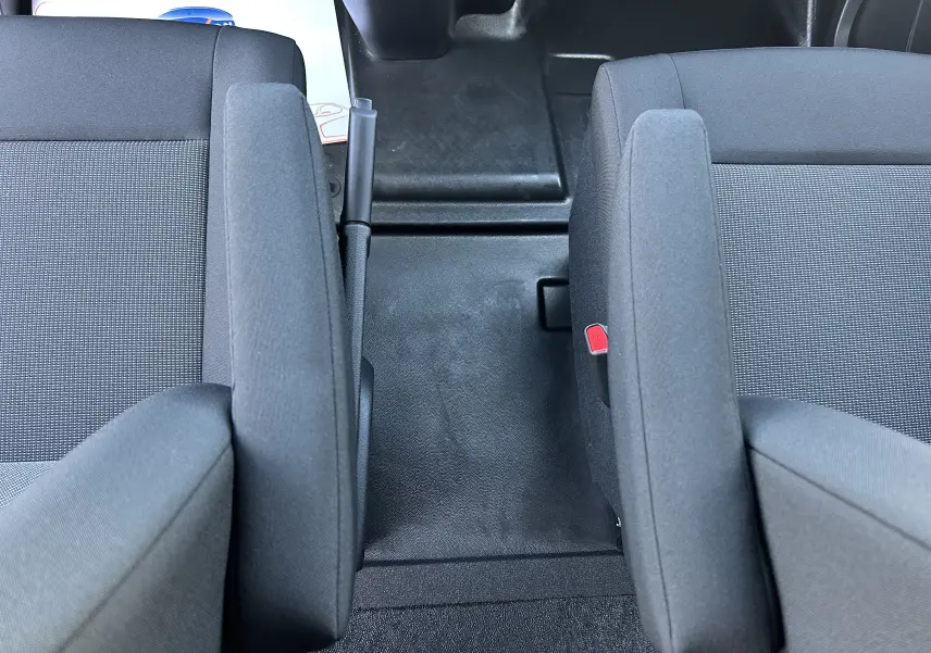 Vue rapprochée de l’intérieur du Citroën Jumpy cabine approfondie 2025, montrant les sièges tissu gris avec accoudoirs et frein à main central.