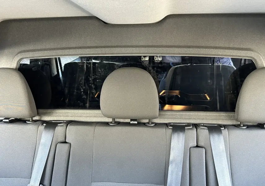 Vue intérieure arrière des sièges gris du Citroën Jumpy Cabine Approfondie noir, avec ceinture de sécurité et vitre séparatrice.