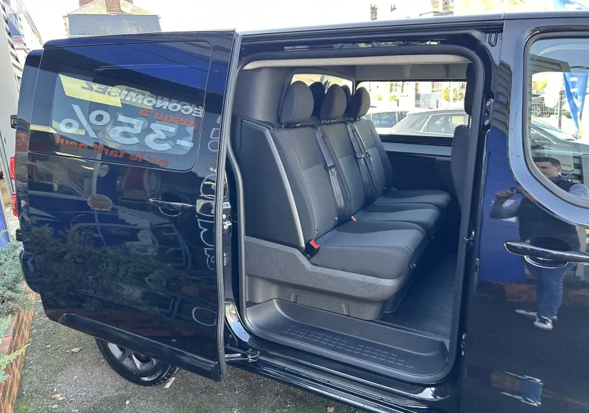 Vue latérale gauche d’un Citroën Jumpy noir avec porte coulissante ouverte révélant la banquette arrière 3 places en tissu.