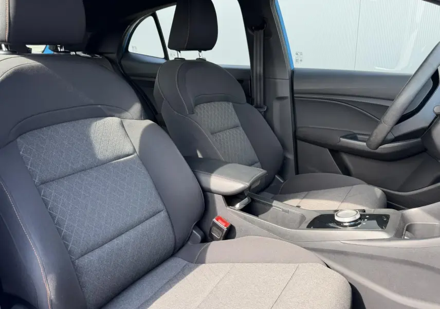 Vue intérieure côté conducteur du MG3 1.5 Hybrid+ 195 Comfort, sièges tissu noir avec accoudoir central et console moderne.