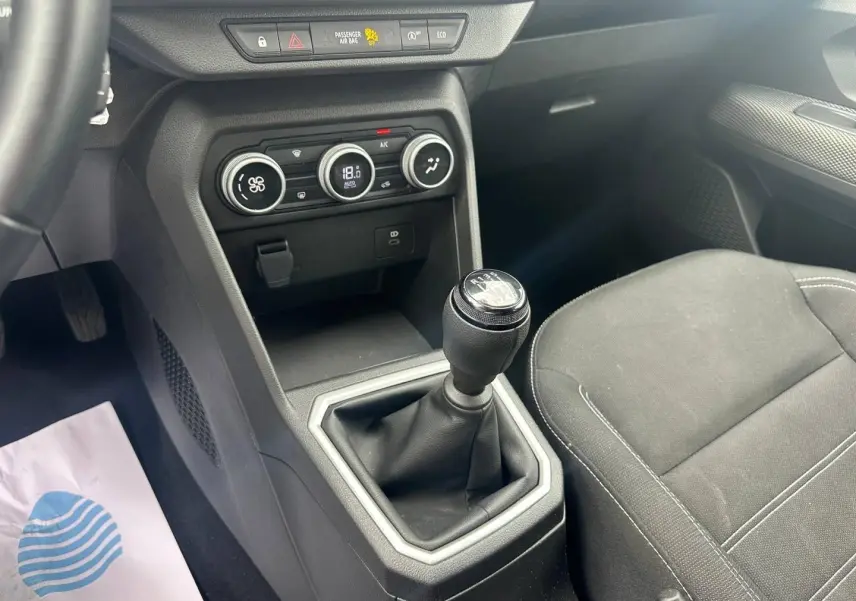 Vue intérieure centrée sur la console centrale et levier de vitesse manuel du Dacia Jogger, sièges tissu noir.