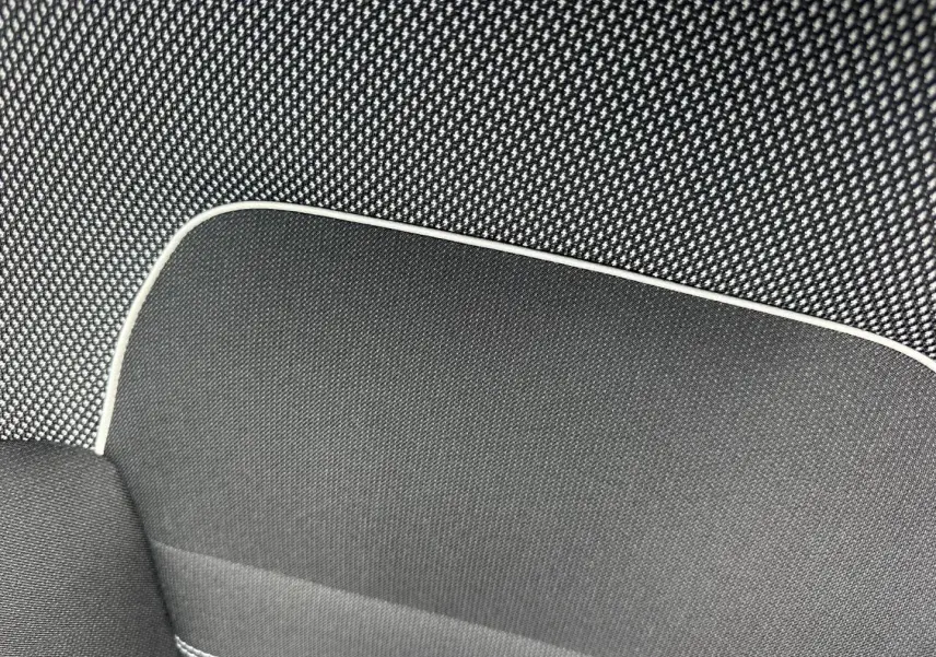 Gros plan sur le tissu noir à motif gris clair avec surpiqûres blanches, intérieur du siège Dacia Jogger Expression.