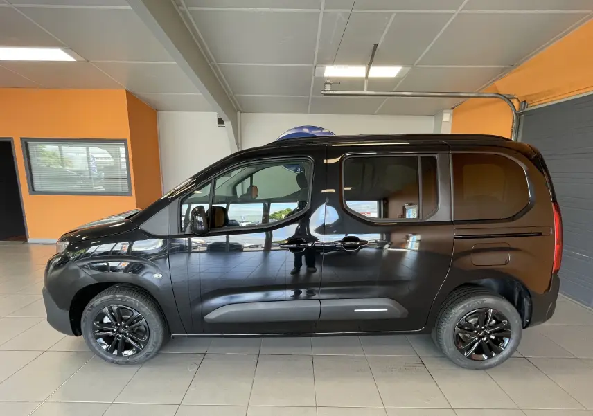 Profil côté gauche du Citroën Berlingo noir 2025 avec jantes noires brillantes, présenté en intérieur showroom.