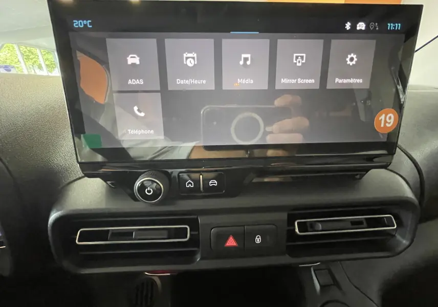 Écran tactile central du tableau de bord du Citroën Berlingo noir 2025, avec commandes climatisation et boutons d'alerte visibles.