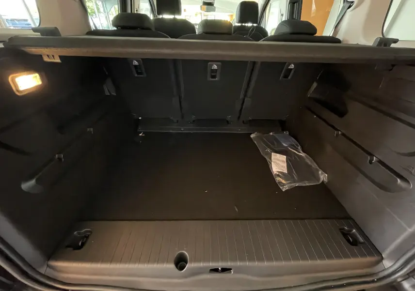 Coffre noir du Citroën Berlingo 2025 vu de l'arrière, avec banquette arrière rabattue et éclairage intérieur allumé.