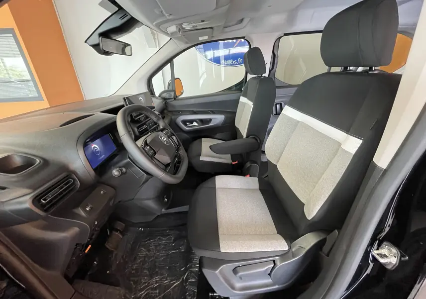 Intérieur du Citroën Berlingo noir 2025 vu côté gauche, sièges bicolores gris et noir avec tableau de bord moderne.