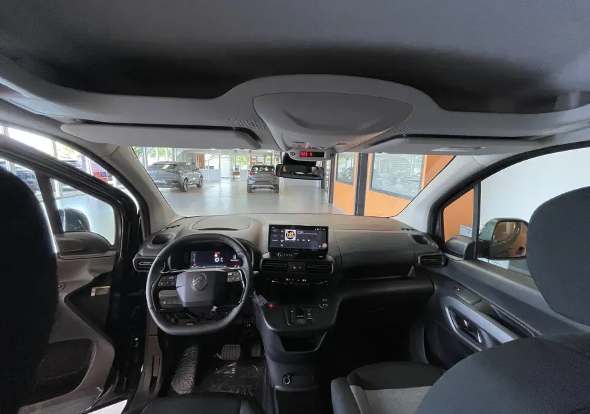 Vue intérieure avant du Citroën Berlingo noir 2025, mettant en valeur le tableau de bord et l'écran tactile central.