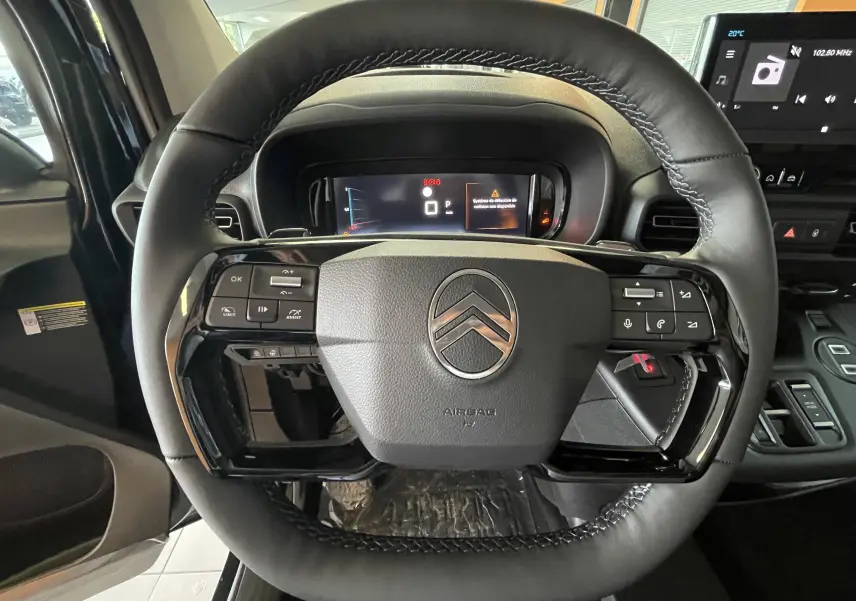 Vue rapprochée du volant noir de la Citroën Berlingo 2025 avec commandes intégrées et tableau de bord numérique.
