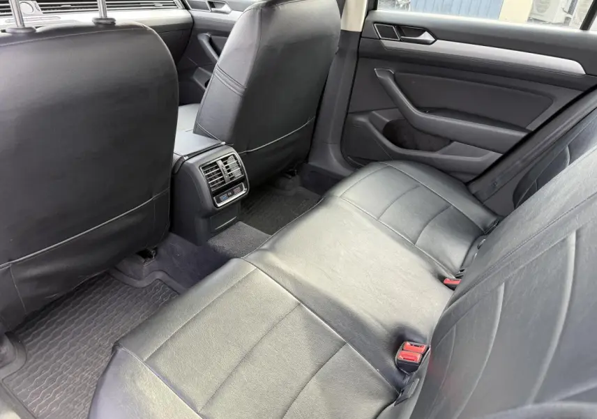 Vue intérieure arrière côté droit de la Volkswagen Passat 2018 avec sièges en cuir noir et aérateurs centraux visibles.
