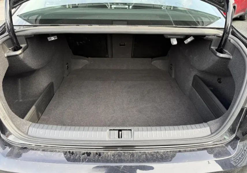 Coffre ouvert d'une Volkswagen Passat noire 2018, vue arrière montrant l'espace de chargement vide et moquetté.