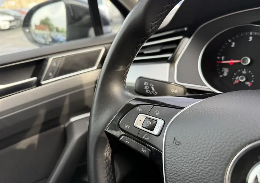 Gros plan sur le volant en cuir noir de la Volkswagen Passat 2018 avec commandes de régulateur de vitesse côté gauche.