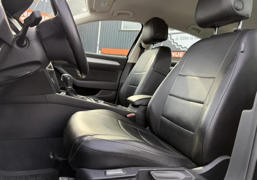 Intérieur avant de la Volkswagen Passat 2018 noir, vue côté conducteur montrant sièges en cuir et console centrale.