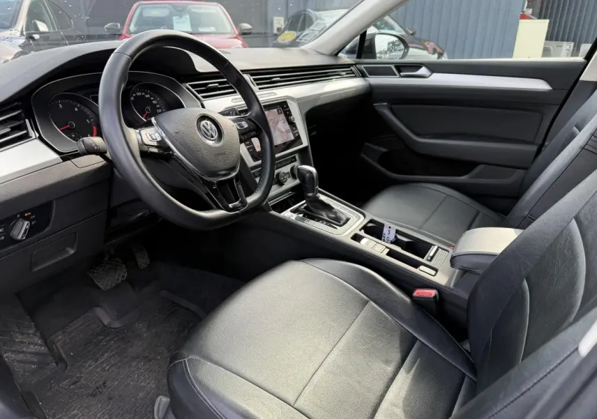 Intérieur avant droit de la Volkswagen Passat 2018 noir, volant cuir multifonction et console centrale avec boîte auto.