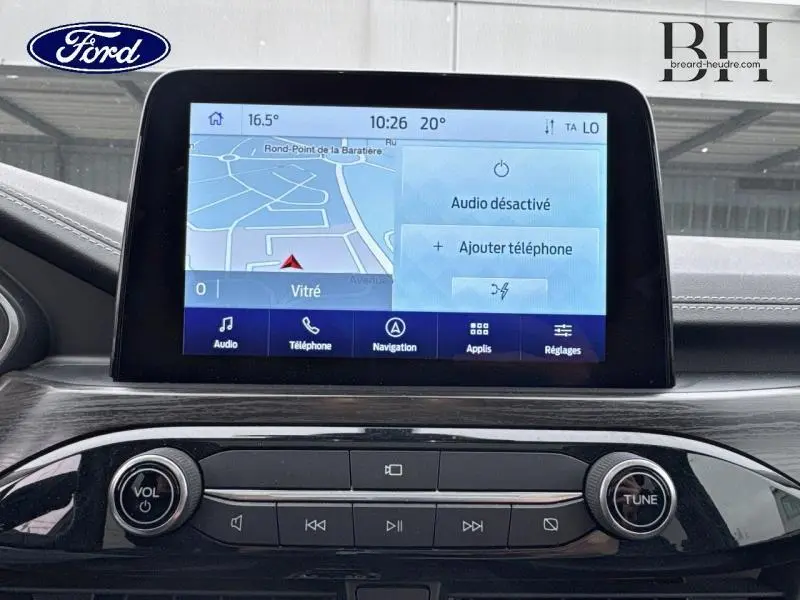 Écran tactile central du Ford Kuga 2022 bleu azur, affichant la navigation et les options audio dans l'habitacle.