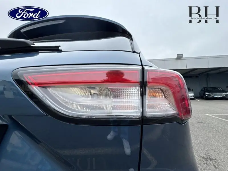 Feu arrière droit du Ford Kuga 2022 bleu azur métallisé avec becquet et toit panoramique visible en arrière-plan.