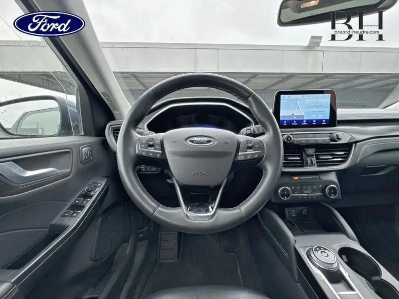 Vue intérieure frontale du poste de conduite du Ford Kuga 2022 avec volant cuir multifonction et écran tactile central.