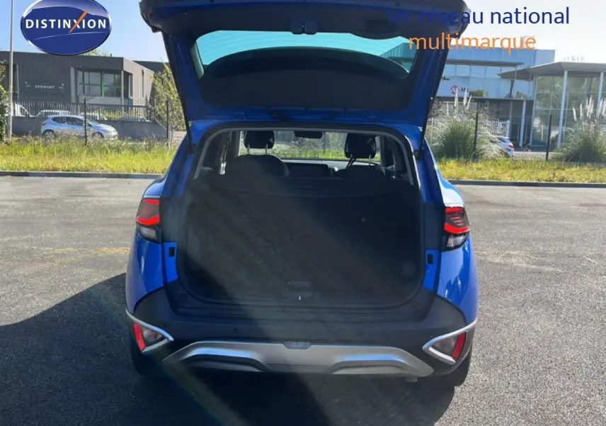 Vue arrière d'un Kia Sportage bleu fusion métal 2022 avec coffre ouvert, mettant en valeur son espace de chargement.