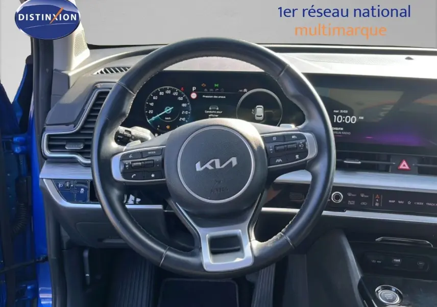Intérieur du Kia Sportage 2022 bleu fusion, vue centrée sur le volant cuir multifonction et tableau de bord numérique.