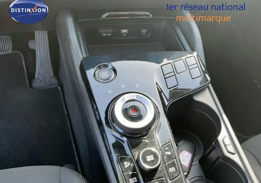 Gros plan sur la console centrale noire brillante du Kia Sportage 2022, montrant la molette de boîte auto et les boutons de contrôle.