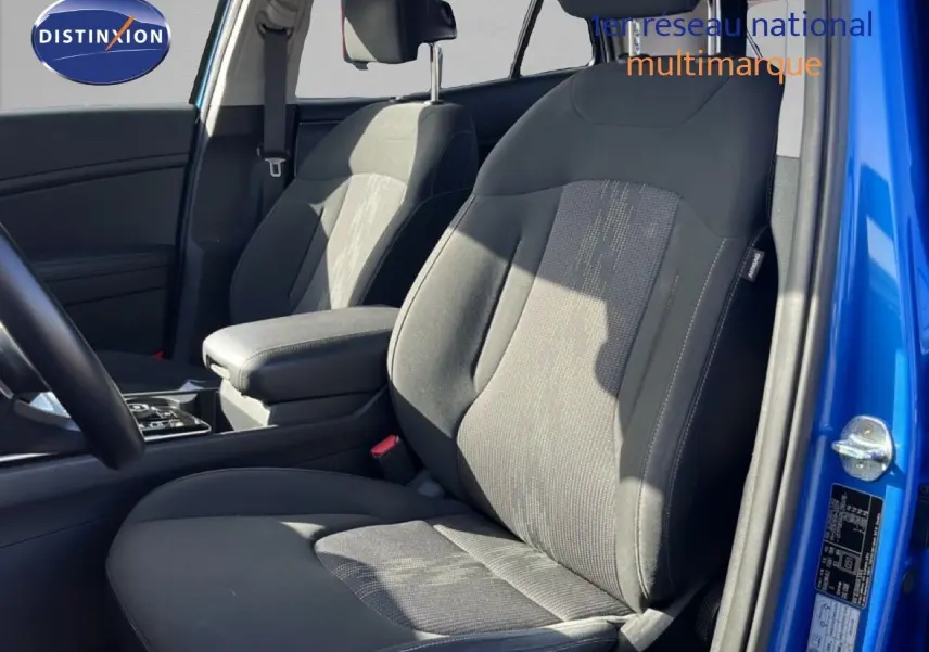 Vue intérieure côté avant droit du Kia Sportage bleu fusion métal 2022, mettant en valeur les sièges tissu noirs et l'accoudoir central.