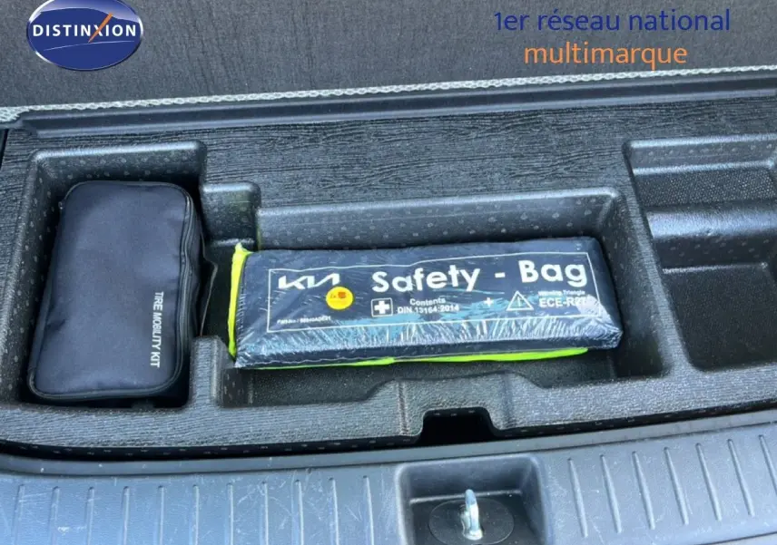Gros plan sur le coffre du Kia Sportage bleu fusion, montrant le kit mobilité et la trousse de sécurité Safety Bag.