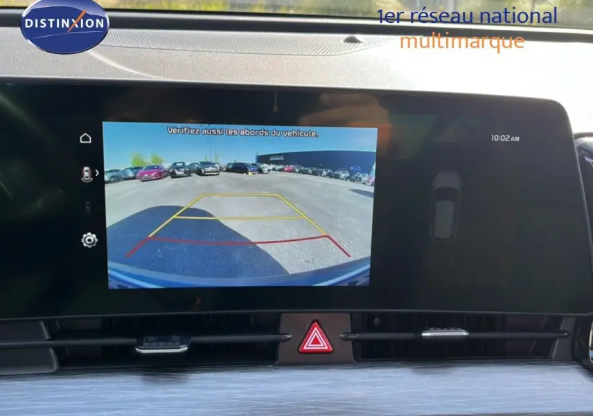 Écran de caméra de recul affichant l'arrière du Kia Sportage bleu fusion métal, vue intérieure du tableau de bord.